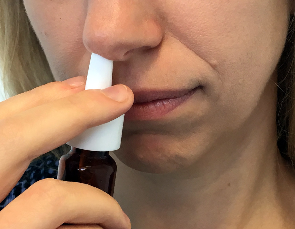 Photo showing woman using nasal spray.