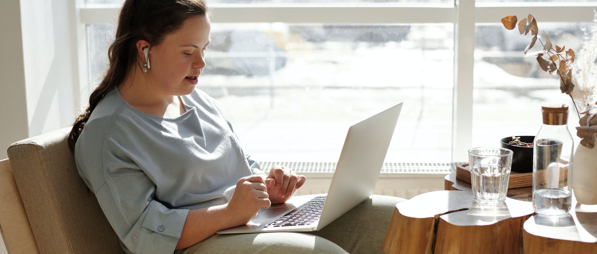 Woman with down syndrome sitting on a couch using a laptop